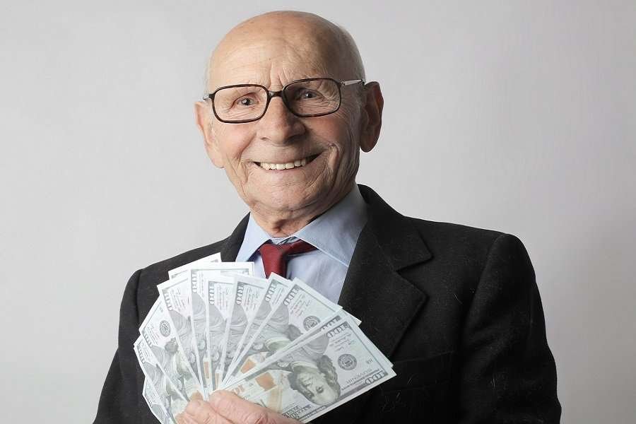 man in black suit holding dollar bills